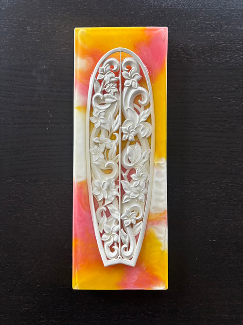 "Plumeria Breeze" surfboard sculpture (2021) – full-size carved surfboard artwork inspired by Hawaiian plumeria and island wind.